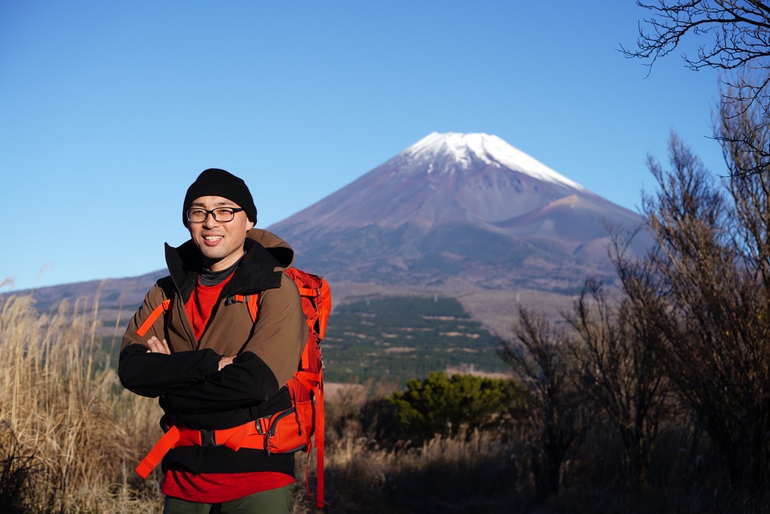 富士山を背景に、登山姿で笑顔の川口健太朗